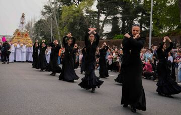 Unas mujeres bailan delante de una estatua de Jesucristo llevada en una plataforma durante una procesión de Semana Santa del Domingo de Ramos, en Madrid, España.