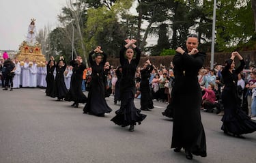 Unas mujeres bailan delante de una estatua de Jesucristo llevada en una plataforma durante una procesión de Semana Santa del Domingo de Ramos, en Madrid, España. 
