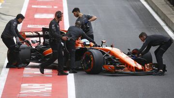 Los mec&aacute;nicos de McLaren empujan a boxes el coche de Alonso en Silverstone.