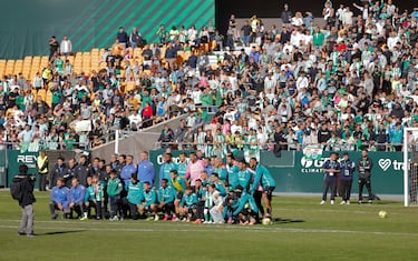 La plantilla del Real Betis posa junta delante del fondo repleto de aficionados béticos.