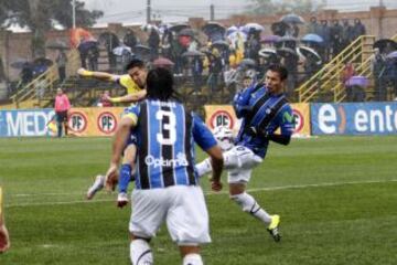Felipe Reynero marca su gol por la U. de Conce sobre Huachipato, mientras de fondo los hinchas se protegen de la torrencial lluvia en la Octava Región.