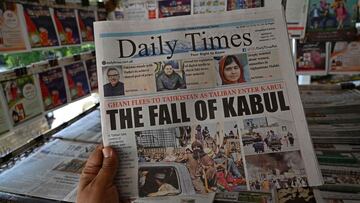 A man holds a newspaper displaying front page news about Afghanistan, at a stall in Islamabad on August 16, 2021.