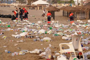 Miembros del servicio de limpieza municipal de Málaga recogen restos de basura en la playa de La Malagueta.