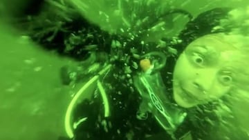 Una submarinista con los ojos muy abiertos sufriendo un ataque de p&aacute;nico bajo el agua, de color verde.