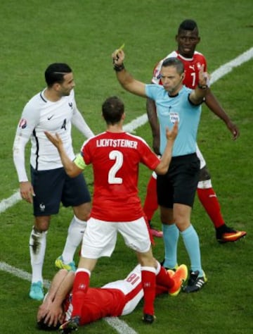 El árbitro Damian Skomina  muestra la tarjeta amrilla a Adil Rami