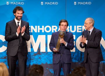 El jugador del Real Madrid, Sergio Llull y el presidente del equipo, Florentino Pérez aplauden mientras el alcalde José Luis Martínez-Almeida sujeta la Copa. 
 