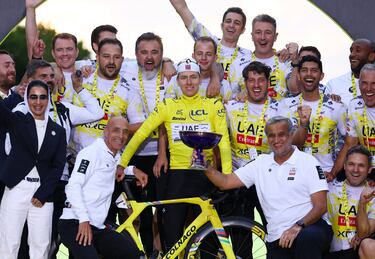 Tadej Pogacar del UAE Team Emirates XRG celebrando en el podio con su bicicleta, trofeo y equipo, tras su victoria en el Tour de Francia.