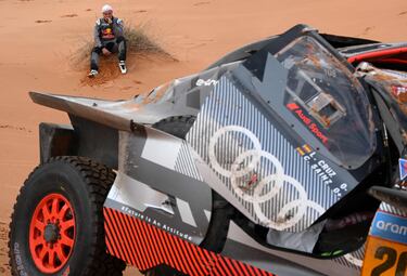 El piloto español de Audi, Carlos Sainz, observa el coche tras haber sufrido un accidente en la etapa de hoy. 