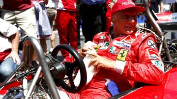 Lauda subido a un Ferrari de su época de piloto.