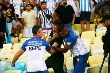 Un aficionado herido es desalojado por miembros de la seguridad del Estadio.