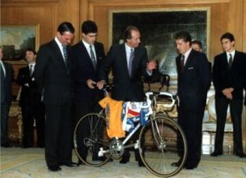 Su Majestad, junto a Mario Conde, Miguel Indurain y Pedro Delgado, sosteniendo una bicicleta con el maillot amarillo del Tour de Francia.