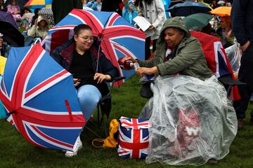 Multitud de personas se acomodan bajo los paraguas en Hyde Park para seguir la ceremonia de coronación.