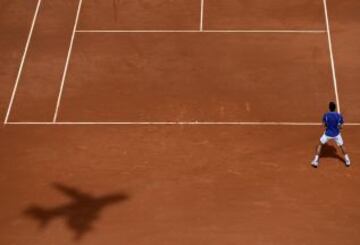 La sombra de una cámara con forma de avión aparece en la pista donde el serbio Novak Djokovic espera un servicio del alemán Philipp Kohlschreiber durante su ronda de Abierto de tenis francés de Roland Garros