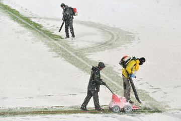 Operarios del club italiano retiran la nieve de las lineas del terreno de juego.