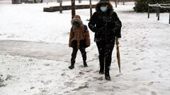 Una mujer y un niño caminan por una calle nevada durante la nevada 'Filomena'. EFE/Beldad