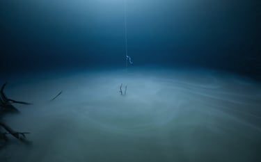 Un instructor de buceo espera a que un alumno salga de una inmersión en Cenote Angelita, en la península de Yucatán. La nube formada por microbios separa el agua dulce de la salada en esta especie de río dentro de otro río. La nube es tan espesa que parece el suelo. "La visibilidad ahí dentro es nula", explica el fotógrafo. 