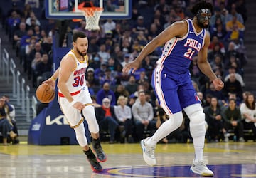 Stephen Curry dribbles past Philadelphia 76ers center Joel Embiid.