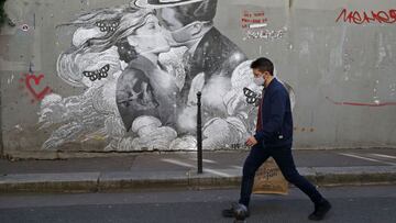 PARIS, FRANCE - MARCH 24: A pedestrian wearing a protective face mask walks past a street-art mural by French street artist 'Treize Bis' (13bis) depicting two lovers wearing protective face masks in reference to coronavirus disease (COVID-19) on March 24, 2021 in Paris, France. The health situation is deteriorating in Paris with very strong pressure on hospitals despite the lockdown of Ile-de-France since last week-end. (Photo by Chesnot/Getty Images)