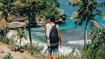 young guy with a beard and a backpack posing in the jungle in a cap