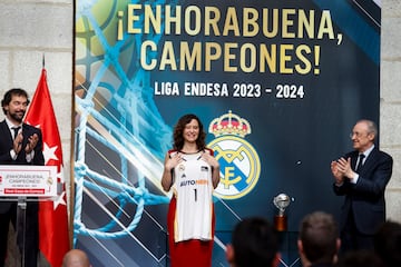 La presidenta de la Comunidad de Madrid, Isabel Díaz Ayuso, recibe una camiseta del Real Madrid de baloncesto como obsequio.