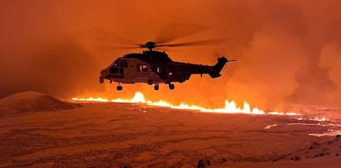 Un helicóptero vuela cerca del volcán que arroja lava y humo mientras entra en erupción cerca de Grindavik. 