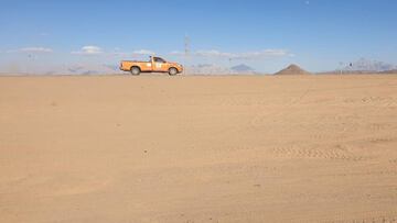 Una camioneta naranja recorre el desierto. 