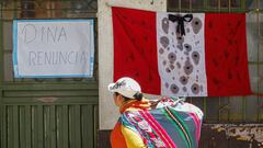 An andean woman walks in front of a sign reading "Dina resigns" in Puno, Peru, on January 10, 2023, a day after 18 people were killed in clashes between demonstrators and security forces. - Peru on Tuesday announced a curfew in the southern Puno region in a bid to suppress violent protests. (Photo by Juan Carlos CISNEROS / AFP) (Photo by JUAN CARLOS CISNEROS/AFP via Getty Images)