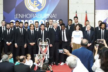 La presidenta de la Comunidad de Madrid, Isabel Díaz Ayuso (3d), acompañada por el presidente del Real Madrid, Florentino Pérez (2d), posa para los medios junto a los jugadores del Real Madrid durante la recepción que ha tenido lugar en la Real Casa de Correos.