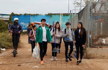 Personas transportan suministros para ayudar a las zonas afectadas por las inundaciones caminan por un camino fangoso, tras las lluvias torrenciales que provocaron inundaciones, en Valencia.