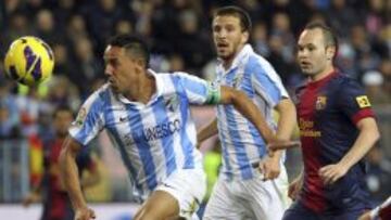El defensa brasileño del Málaga Weligton escapa de Andrés Iniesta, del FC Barcelona, durante el partido de Liga disputado esta noche en el estadio de la Rosaleda, en Málaga.
