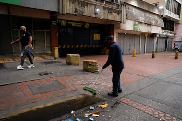 Un hombre barre la calle cercana a su negocio tras el ataque estadounidense sobre Caracas.