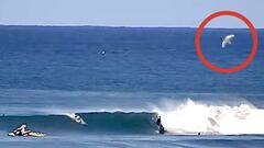 Un tibur&oacute;n blanco salta arriba a la derecha, rodeado con un c&iacute;rculo rojo, mientras varios surfistas surfean la secci&oacute;n de Supertubes de Jeffreys Bay (Sud&aacute;frica) el 11 de julio del 2022. 