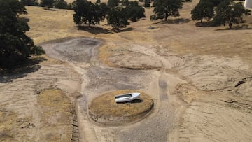 A lone boat sits perched on a mound near Hensley Lake as soaring temperatures and drought continue to affect livestock and water supplies in Madera, California, July 14, 2021.