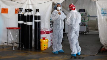Healthcare workers wearing personal protective equipment (PPE) stand outside one of the temporary wards dedicated to the treatment of possible COVID-19 coronavirus patients at Steve Biko Academic Hospital in Pretoria on January 19, 2021. (Photo by Phill Magakoe / POOL / AFP)