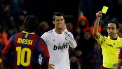 Real Madrid's Cristiano Ronaldo (C) receives a yellow card from referee Eduardo Iturralde Gonzalez as Barcelona's Leo Messi (L) looks on during their Spanish first division soccer match at Nou Camp stadium in Barcelona, November 29, 2010.  REUTERS/Albert Gea (SPAIN  - Tags: SPORT SOCCER)  