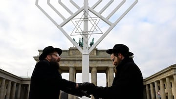 Rabbis Yehuda Teichtal (L) and Shmuel Segal sing and dance as they consecrate a giant menorah in front of the Brandenburg Gate in Berlin on December 16, 2022, as preparations are under way for Hanukkah (or Chanukkah), an eight-day Jewish celebration. (Photo by John MACDOUGALL / AFP) (Photo by JOHN MACDOUGALL/AFP via Getty Images)