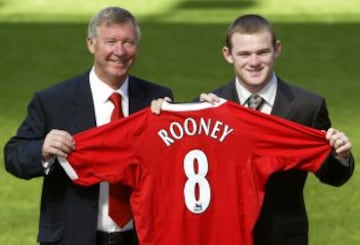 Wayne Rooney levanta la camisa del club con el entrenador Sir Alex Ferguson en el campo en Old Trafford tras su fichaje por el Manchester United