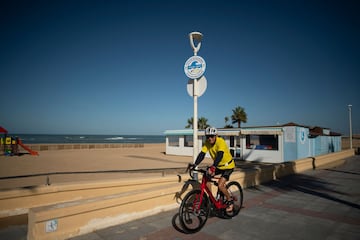 Un ciclista, en el paseo marítimo bajo un cartel que indica el simulacro de tsunami. (Photo by JORGE GUERRERO / AFP)