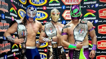 Star Jr., (izq), Máscara Dorada (centro) y Star Jr. (der) posan con los cinturones de campeones Mundiales de Tríos.