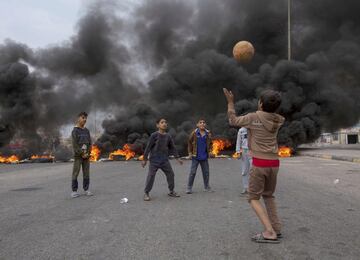 Desde que comenzaron las protestas sociales en Irak, más de 340 personas han fallecido como consecuencia de los disturbios callejeros. La población exige mejoras en los servicios públicos y la dimisión del Gobierno.  En la imagen, varios niños juegan a la pelota junto a una barricada en Basora, ciudad situada al sur del país.
