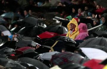 Los aficionados se protegen de la lluvia en el estadio Sánchez Pizjuan.