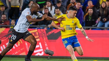 El centrocampista de Las Palmas Alberto Moleiro juega un balón ante Dimitri Foulquier, del Valencia.