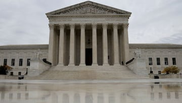 The US Supreme Court building is reflected on wet marble.