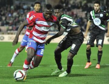 El delantero nigeriano del Granada CF Isaac Success se escapa del camerunés Patrick Ekeng, del Córdoba, durante el partido de dieciseisavos de final de la Copa del Rey que se disputa esta noche en el estadio Nuevo Los Cármenes, en Granada. 