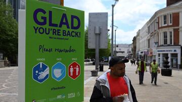 A pedestrian walks past a sign welcoming members of the public back to the town centre, but asking them to adhere to government guidleines, in Blackburn, north west England on June 16, 2021. - The UK government on Monday announced a four-week delay to the full lifting of coronavirus restrictions in England due to a surge in infections caused by Delta, which first appeared in India. (Photo by Oli SCARFF / AFP)