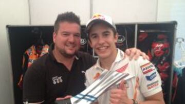 FINAL DISTENDIDO DE GRAN PREMIO. Es algo de sobra conocido que Márquez no pierde su sonrisa ni en los peores momentos. Este no es el caso, puesto que ha vencido en los tres grandes premios que van de Mundial y se encuentra en un momento dulce de su carrera, y así de contento se muestra posando junto al enviado especial de AS al Mundial de motociclismo. Marc disfruta mostrando su trofeo de ganador del gran premio y bebiendo de la botella de champán que les dan en el podio.