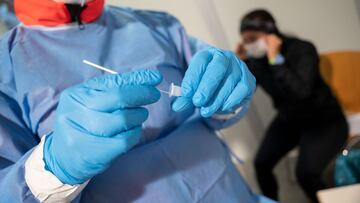 23 December 2020, Baden-Wuerttemberg, Stuttgart: A volunteer of the German Red Cross (DRK) performs a Corona rapid test at a testing station in Stuttgart. Tens of thousands of people across Germany are rushing for Coronavirus tests before Christmas Eve. P