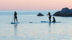 Tres surfistas en tabla de SUP recogiendo micropl&aacute;sticos de la playa de la Barceloneta, en Barcelona. 