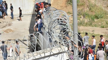 Fnideq (Morocco), 18/05/2021.- Migrants climb the fence in the northern town of Fnideq in an attempt to cross the border from Morocco to the Spanish enclave of Ceuta, in North Africa 18 May 2021. In little over 24 hours a total of almost 8,000 people entered into the Spanish city of Ceuta, located in the North African coast, by sea side and hundreds of migrants continue to attempt doing so. The Spanish authorities have deployed the army to patrol on the border separating Ceuta in the Spanish side from the Moroccan side, in a bid to control this latest surge of entry attempts. (Marruecos, España) EFE/EPA/JALAL MORCHIDI