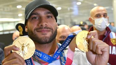 Italy's 100m and 4x100m relay gold medal winner Lamont Marcell Jacobs poses with his medals as he arrives from the 2020 Tokyo Olympics at Rome's Fiumicino Airport on August 9, 2021. (Photo by Alberto PIZZOLI / AFP)